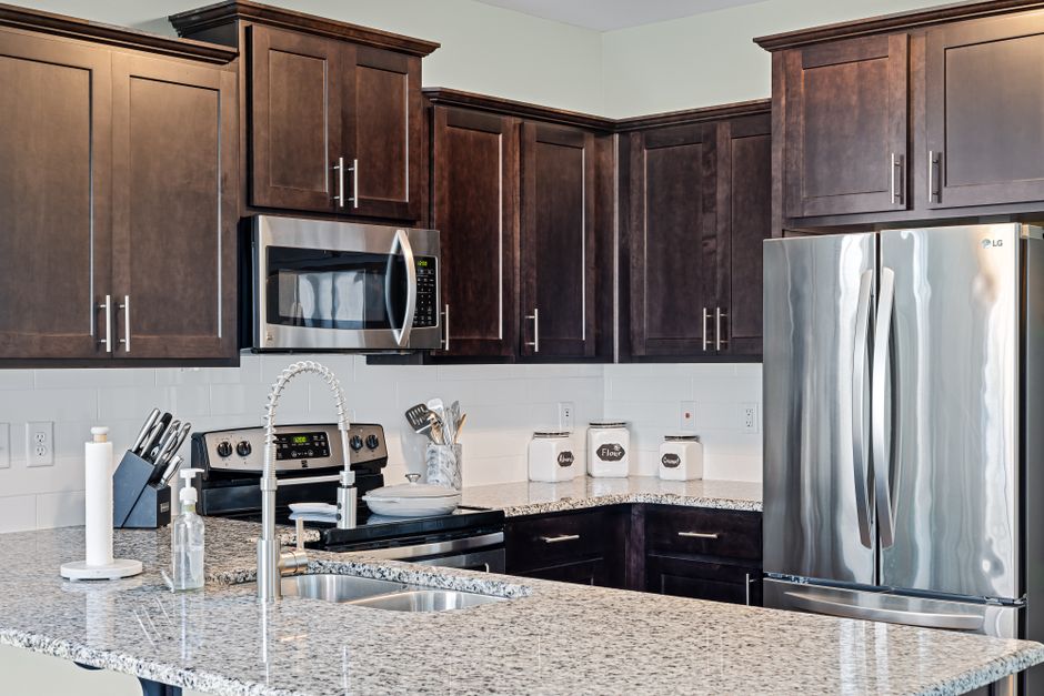 Stylish kitchen featuring dark wood cabinets, granite countertops, and stainless steel appliances.