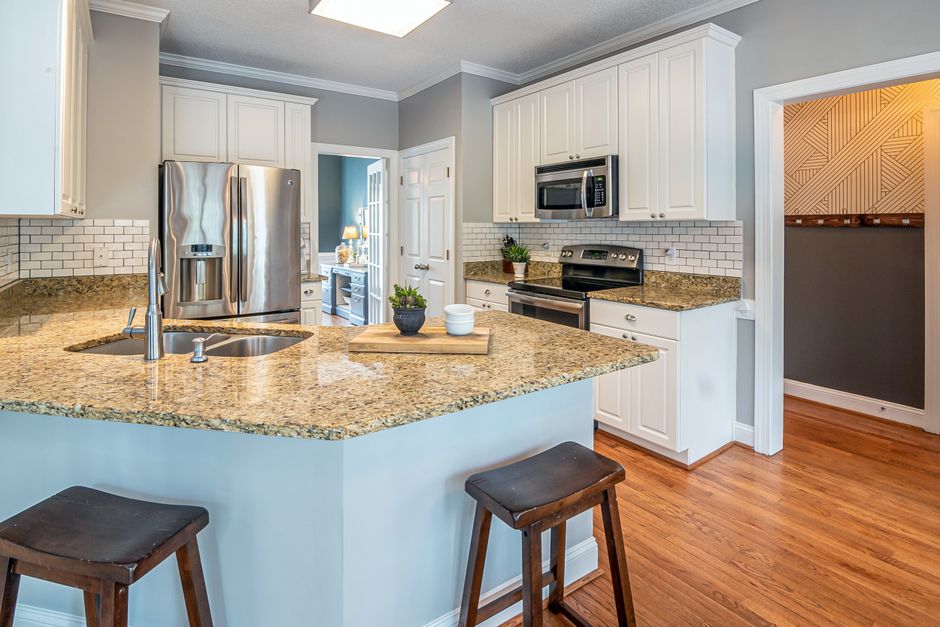 A bright modern kitchen with granite countertops and stainless steel appliances.