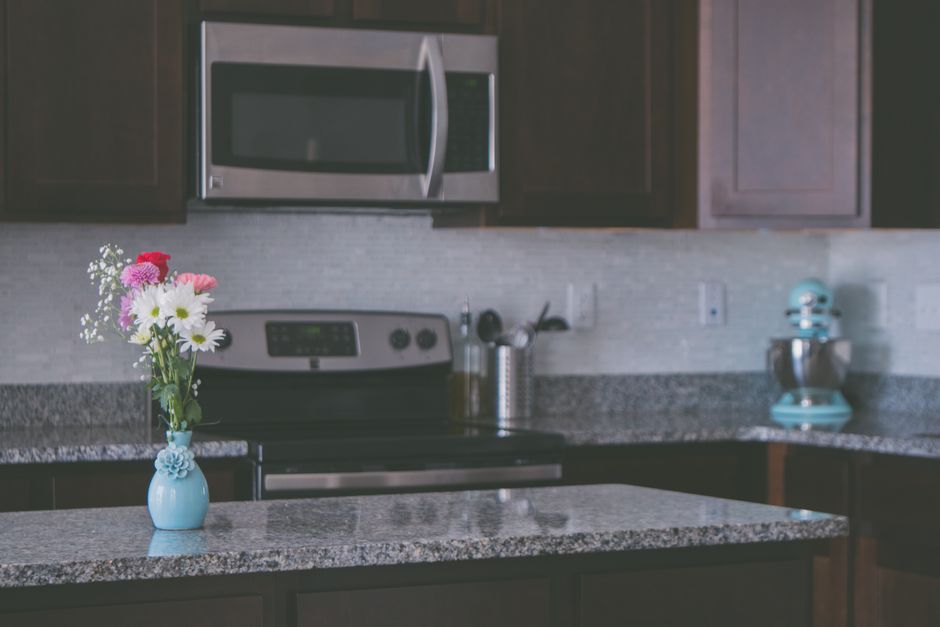 A contemporary kitchen featuring granite countertops and a vase of colorful flowers, creating a warm ambiance.
